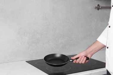 Aşçı tavayı mutfağın üstünde tutuyor, yakın plan.