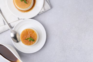 Tasty pudding with caramel sauce served on white table, flat lay. Space for text