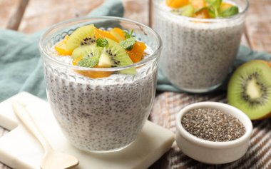 Delicious chia pudding with kiwi, peach and mint in glasses served on table, closeup