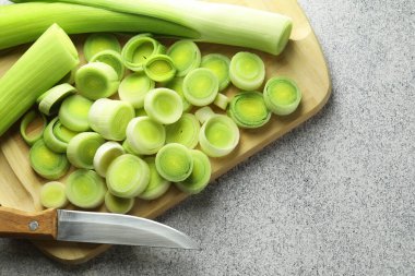 Chopped leeks and knife on grey table, top view. Space for text