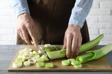 Gri ahşap masada pırasa kesen kadın, yakın plan.