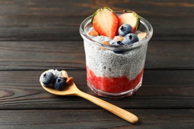 Çilekli Chia pudingi, yaban mersini ve bademler ahşap masada, yakın plan.