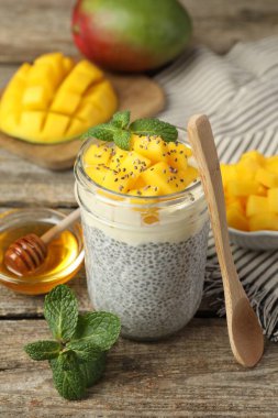Bardakta mangolu lezzetli chia pudingi, ahşap masada nane ve bal, yakın plan.