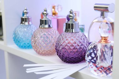 Dükkandaki raflarda farklı parfüm şişeleri ve parfümler var.