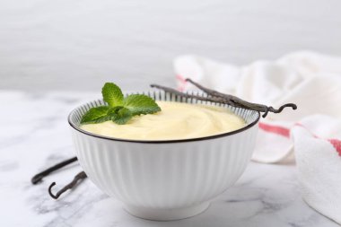 Lezzetli vanilyalı puding, nane ve kapsüller beyaz mermer masada, yakın plan.