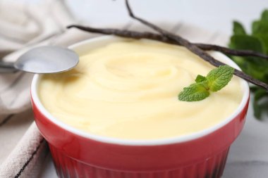 Tasty vanilla pudding, mint and pods on white table, closeup