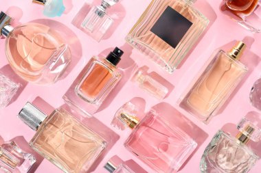 Pembe arka planda çeşitli parfüm şişeleri, düzlük