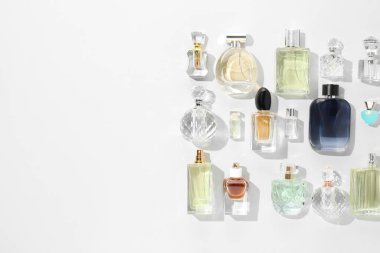 Bottles of various perfumes on white background, flat lay. Space for text