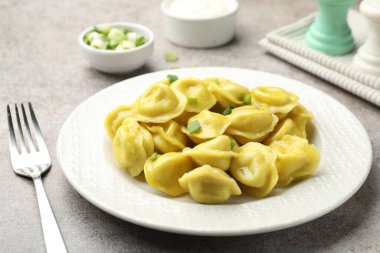 Gri desenli masada yeşil soğan ve çatallı lezzetli hamur tatlısı, yakın plan.