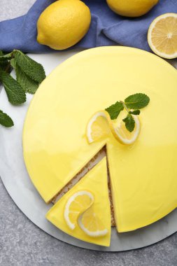 Tasty lemon cheesecake, mint and citrus fruits on grey textured table, flat lay