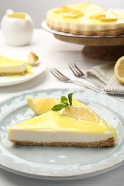 Beyaz ahşap masada servis edilen limonlu nefis peynirli kek, yakın plan.