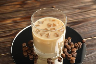 Bardakta kremalı kahve likörü ve ahşap masada fasulye, yakın plan.