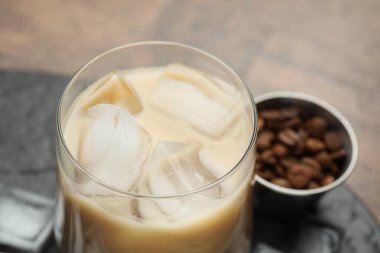 Coffee cream liqueur in glass, ice cubes and beans on table, closeup