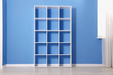 Empty shelving unit near blue wall indoors