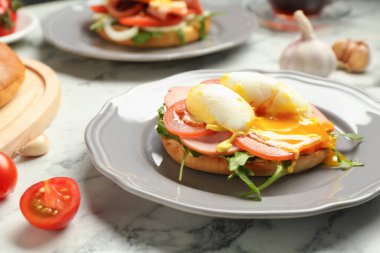 Lezzetli bir kahvaltı. Haşlanmış yumurta, jambon, domates, roka ve ekmek beyaz mermer masada, yakın plan.