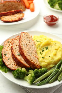 Delicious baked turkey meatloaf with mashed potato served on white table, closeup