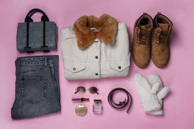 Stylish outfit with warm jacket and accessories on light pink background, flat lay