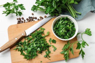 Fresh parsley, knife and pepper on white marble table, flat lay