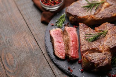 Pieces of delicious beef meat and spices on wooden table, closeup. Space for text