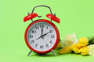 Bahar geldi. Çalar saat ve yeşil arkaplanda güzel çiçekler