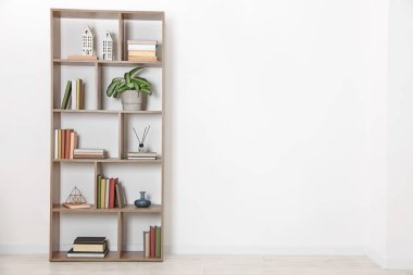 Wooden shelving unit with different home decor and houseplant near white wall indoors, space for text