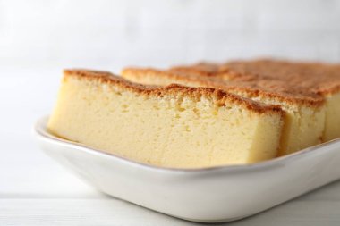 Tasty Japanese Castella sponge cake on white wooden table, closeup