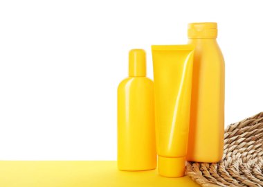 Different sun protection products on yellow surface against white background