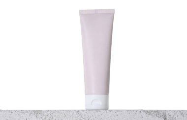 Beton yüzeyde beyaz arkaplana karşı güneş koruma ürünü tübü