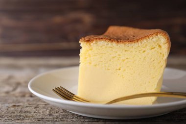 Piece of tasty Japanese Castella sponge cake and fork on wooden table, closeup