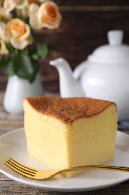 Piece of tasty Japanese Castella sponge cake and fork on table, closeup