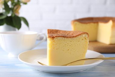Tasty Japanese Castella sponge cake and fork on light blue wooden table, closeup