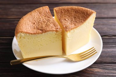 Pieces of tasty Japanese Castella sponge cake and fork on wooden table, closeup