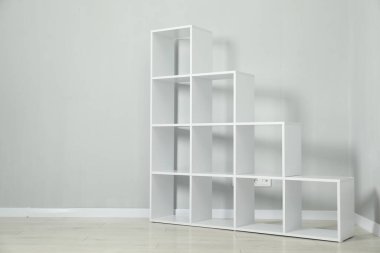 Empty shelving unit near light grey wall indoors, space for text