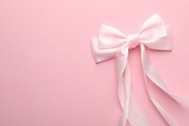 Hair bow on pink background, top view. Space for text