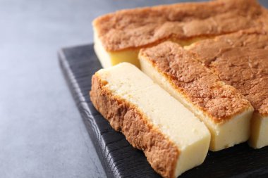 Tasty Japanese Castella sponge cake on grey table, closeup. Space for text