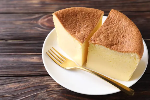 Pieces of tasty Japanese Castella sponge cake and fork on wooden table, closeup. Space for text