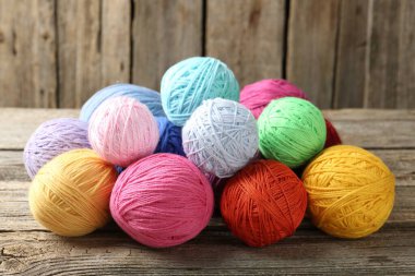 Balls of colorful yarn on wooden table, closeup