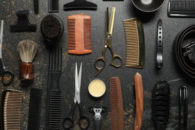 Many different barber's tools on black textured table, flat lay