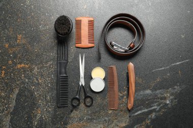 Many different barber's tools on black textured table, flat lay