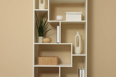 Shelving unit with decor near beige wall indoors
