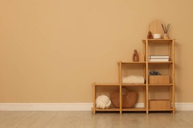 Shelving unit with decor near beige wall indoors, space for text