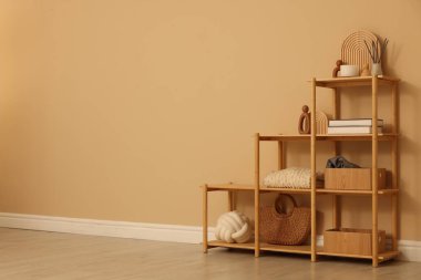 Shelving unit with decor near beige wall indoors, space for text