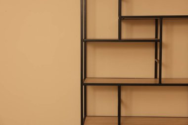 Empty shelving unit near beige wall indoors, closeup. Space for text