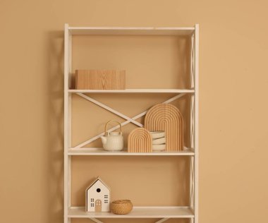 Shelving unit with decor near beige wall indoors