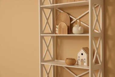 Shelving unit with decor near beige wall indoors, space for text