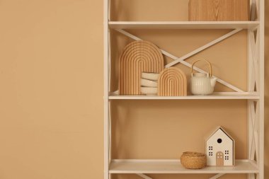 Shelving unit with decor near beige wall indoors, space for text
