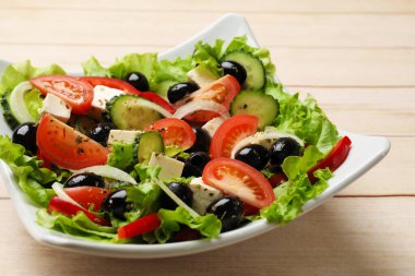 Beyaz ahşap masada leziz taze Yunan salatası, yakın plan.