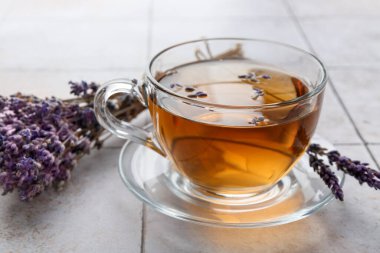 Cam bardakta Aromatik lavanta çayı ve beyaz fayanslı masada kuru çiçekler, yakın plan.