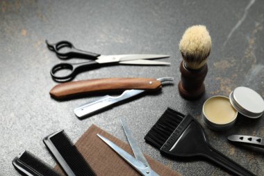 Many different barber's tools on black textured table, closeup