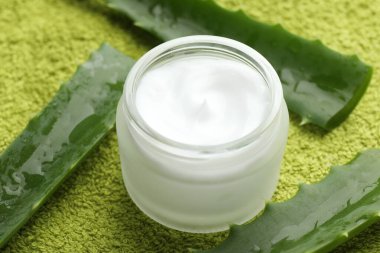 Yeşil arkaplanda krema ve aloe yaprakları, yakın plan